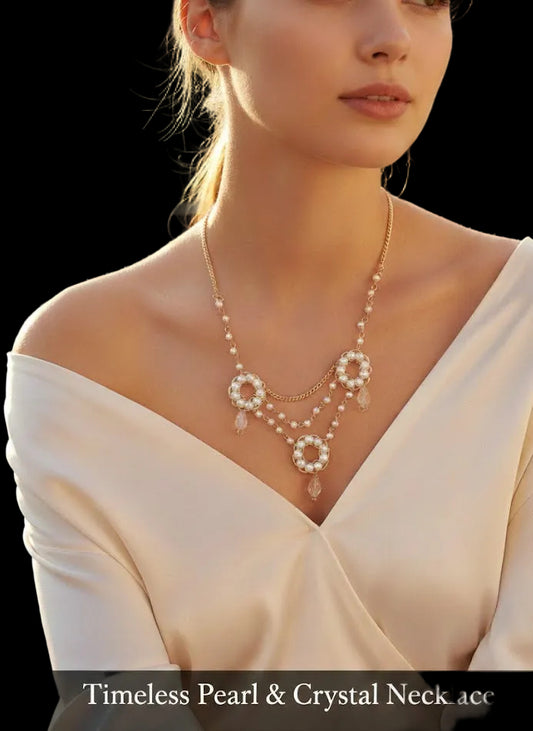 Close-up of a woman wearing the Timeless Pearl & Crystal Necklace featuring three ornate circular pearl pendants, gold-tone tiered chains, and clear teardrop crystal accents against a cream-colored silk blouse.