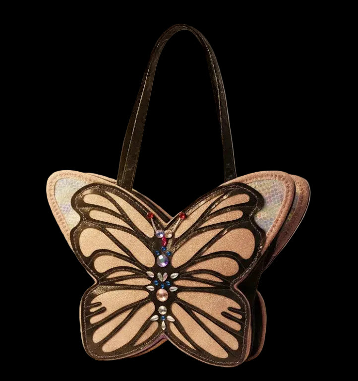 Close-up of a unique butterfly-shaped fashion Luxury bag. The wings feature a shimmering holographic texture with black embroidery, while the center is decorated with blue, red, and clear rhinestones against a velvet-textured background.
